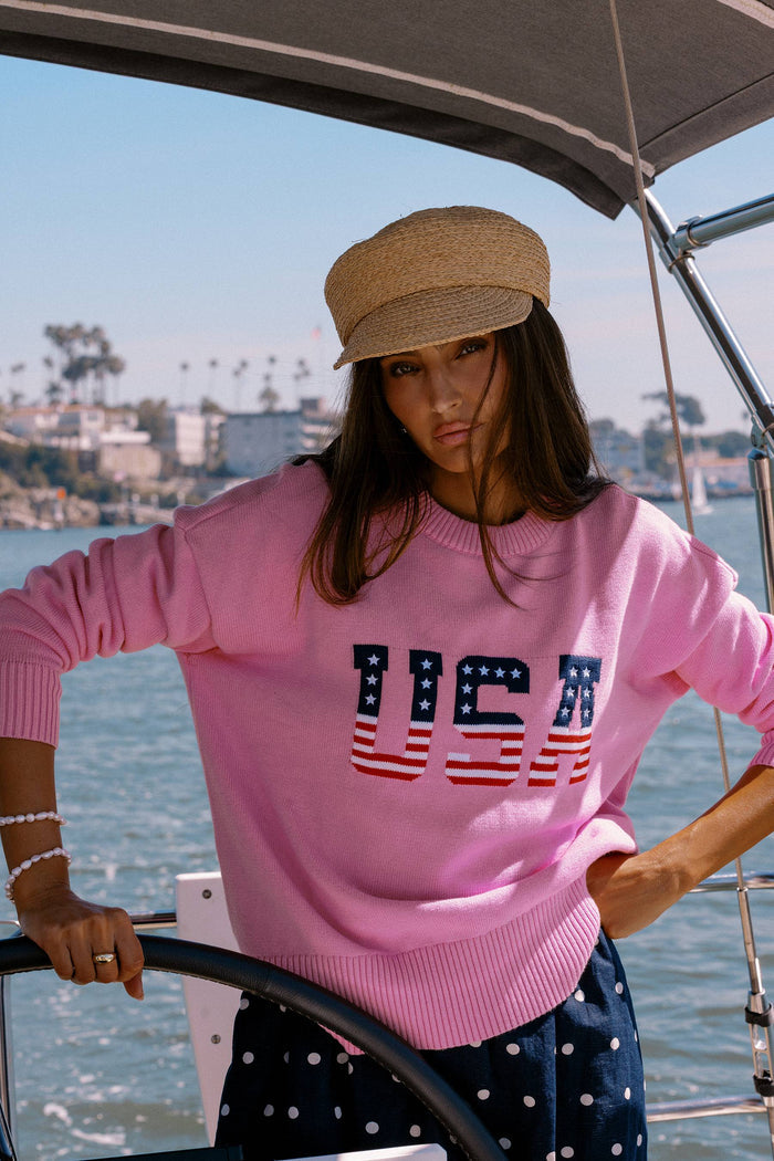 Person wearing a pink sweater with 'USA' print on a boat