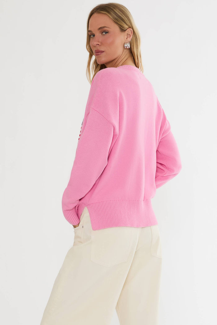 Person wearing a pink sweater and white pants on a light gray background