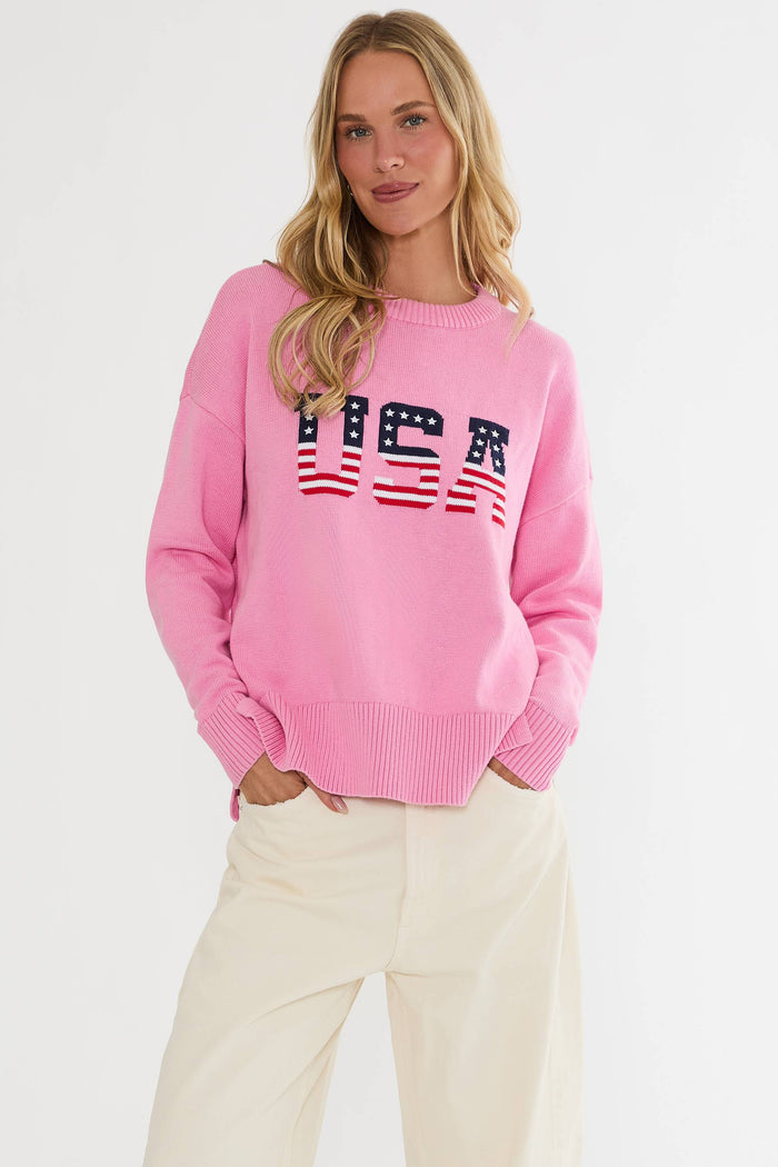 Woman wearing a pink sweater with 'USA' text and American flag design on a white background
