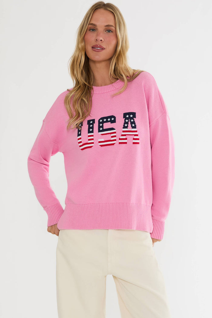 Woman wearing a pink sweater with 'USA' text on a white background