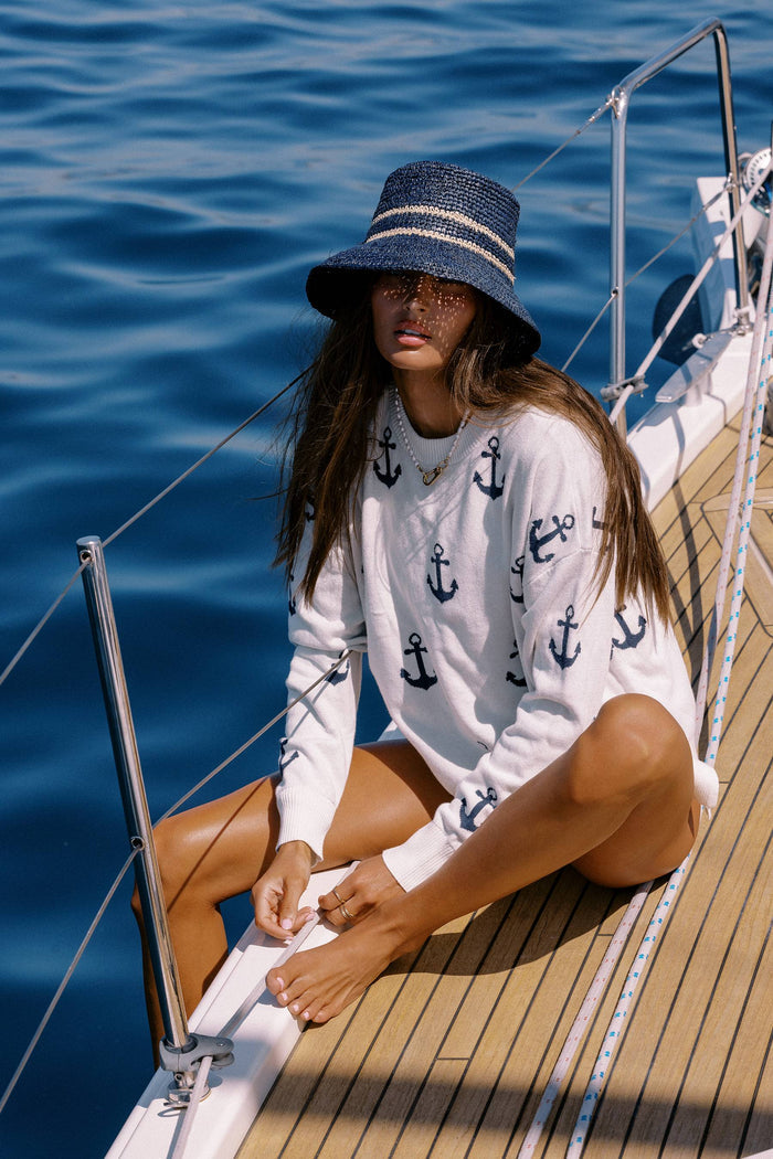 White sweater with navy anchors on it.
