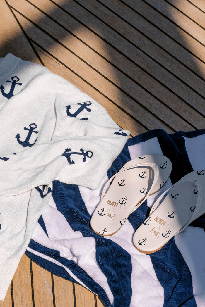 White sweater with navy anchors on it.