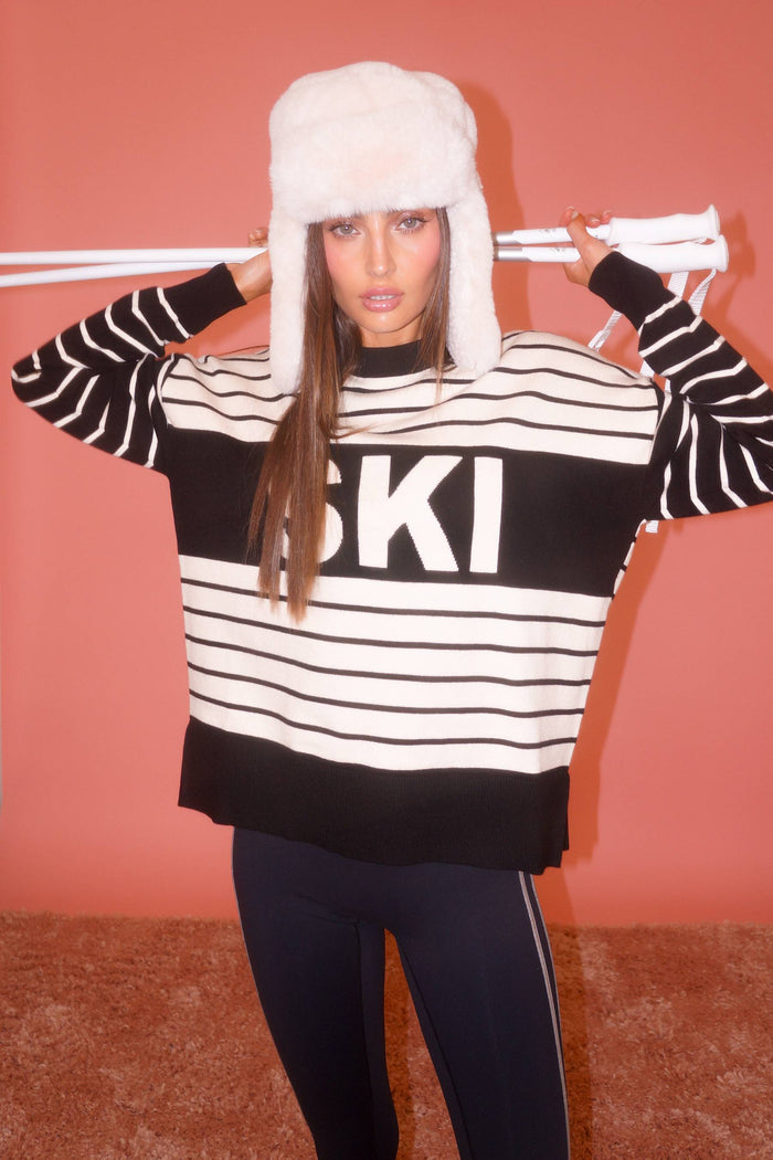 Woman wearing a black and white striped sweater with 'SKI' text on a plain background