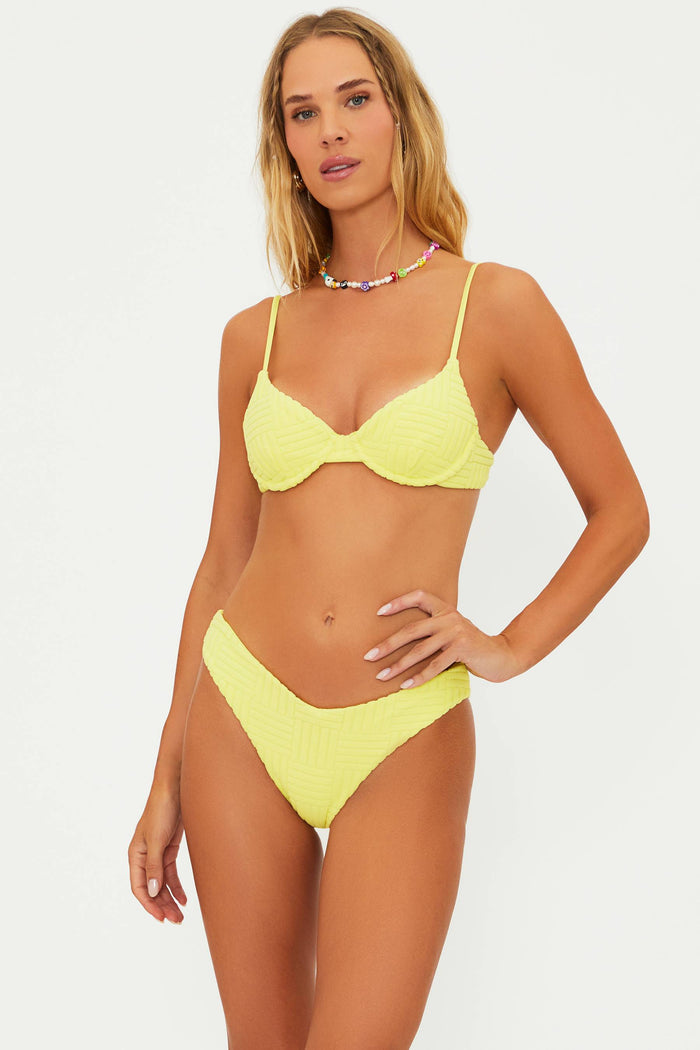 A model wearing a yellow underwire bralette style swim top with adjustable straps and a matching bottom, accessorized with a necklace.