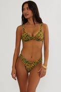 Woman wearing a green and yellow floral bikini against a white background