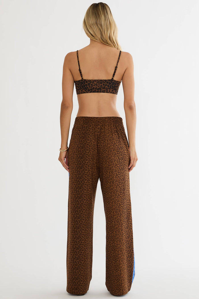 A woman shown from the back wearing a matching brown leopard-print outfit, consisting of a spaghetti-strap crop top and high-waisted wide-leg pants, against a plain white studio background.