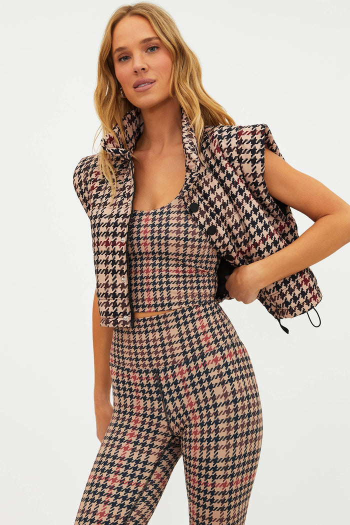 Woman wearing a houndstooth patterned outfit with a vest on a white background