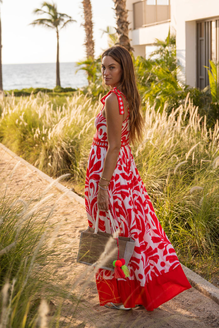 woman by the beach in an orange floral maxi dress