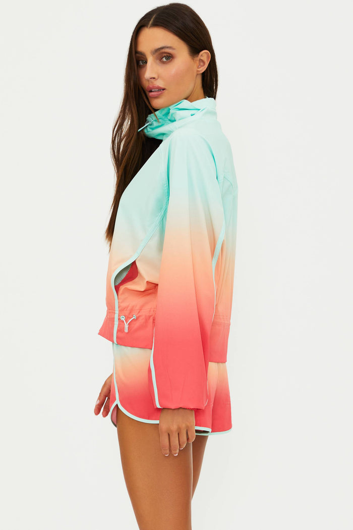 Woman wearing a colorful gradient jacket with a visible brand logo on a white background
