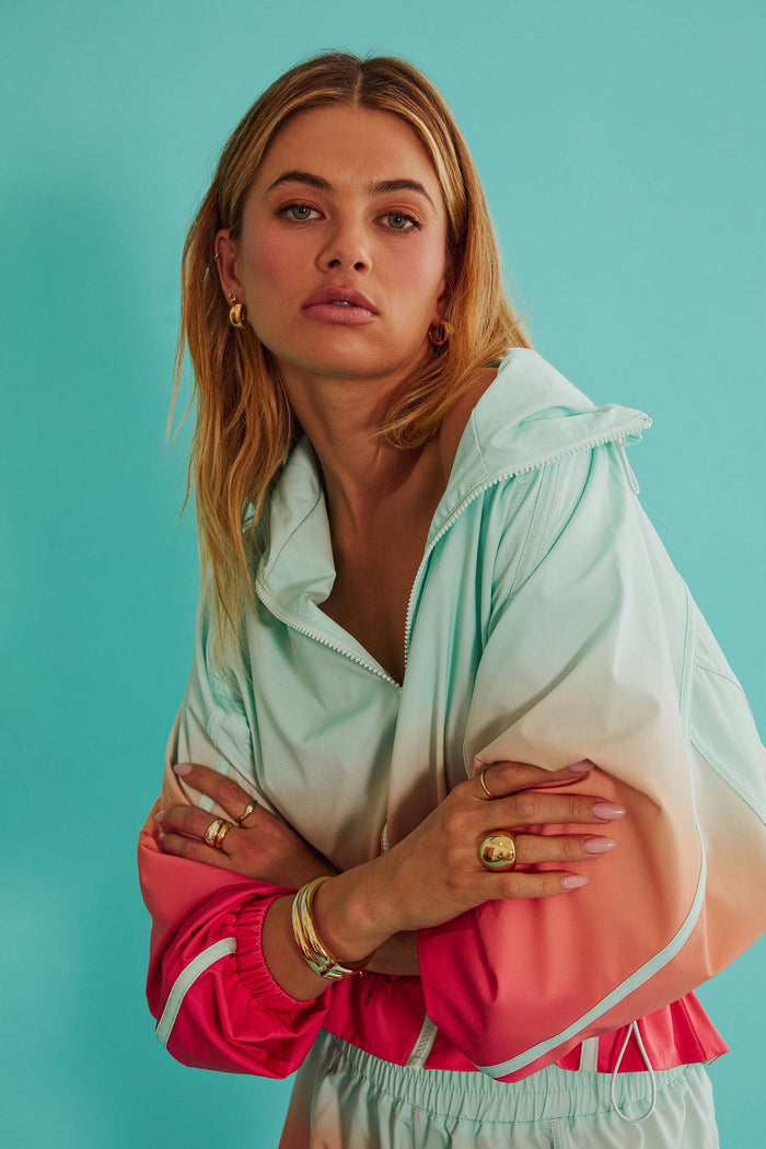 Woman wearing a colorful jacket with a gradient effect against a teal background