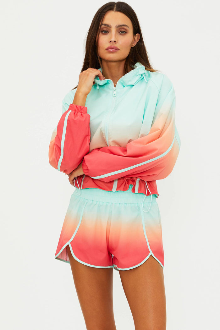 Woman wearing a colorful ombre hoodie and shorts set on a light gray background