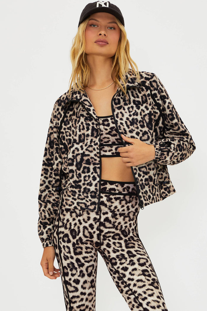 Person wearing a leopard print outfit with a black cap on a white background