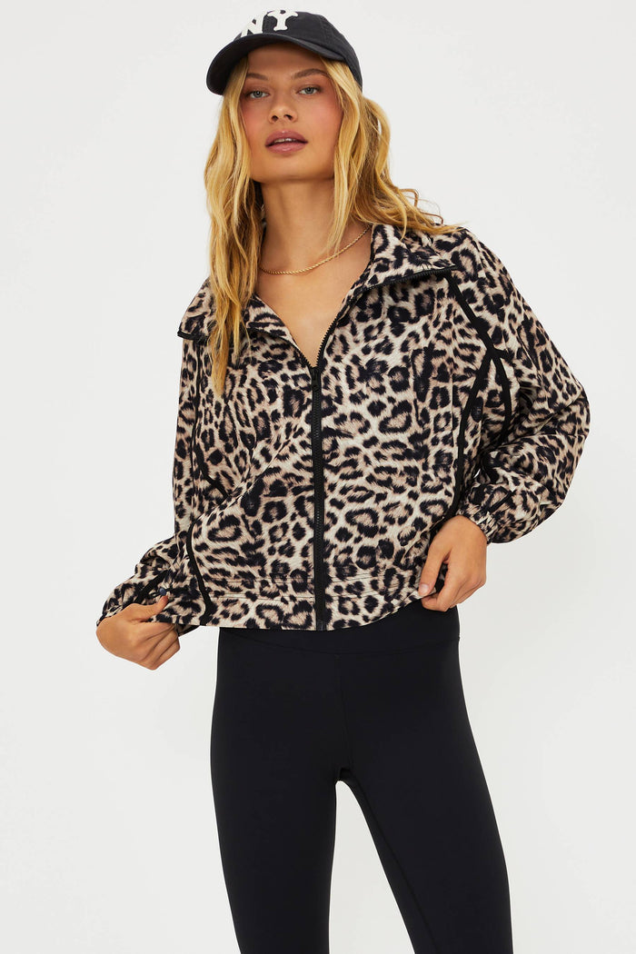 Woman wearing a leopard print jacket and black cap on a white background