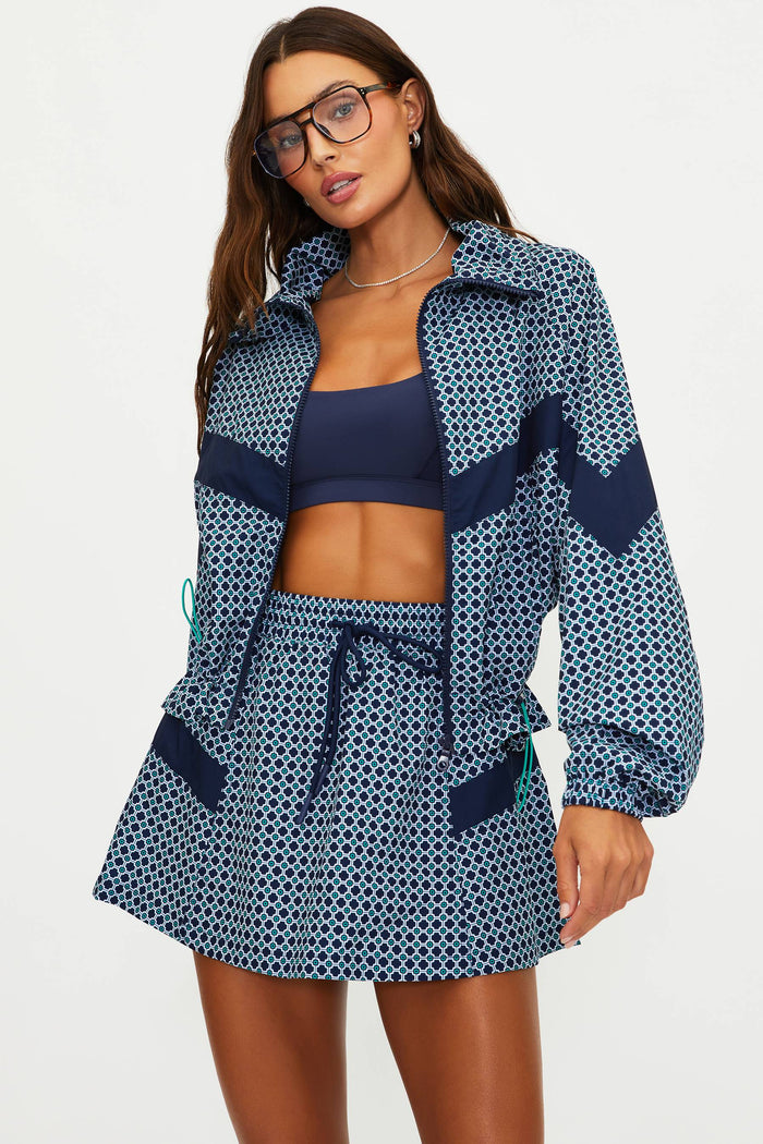 Woman wearing a blue patterned outfit with a jacket and skirt on a white background
