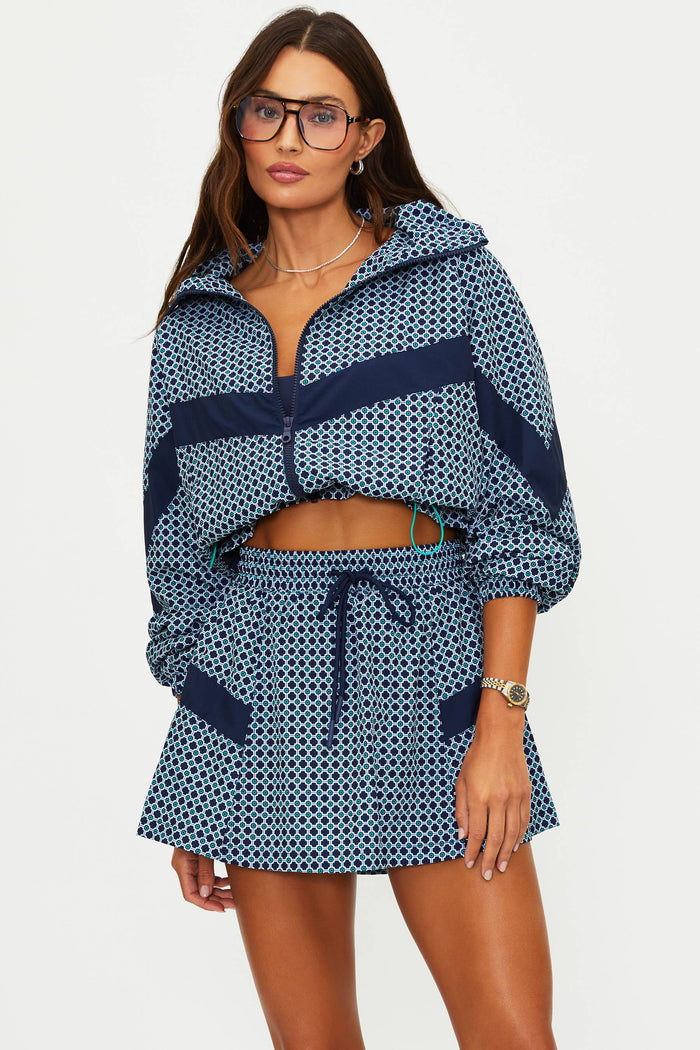 Woman wearing a blue patterned outfit with a matching jacket and skirt on a white background