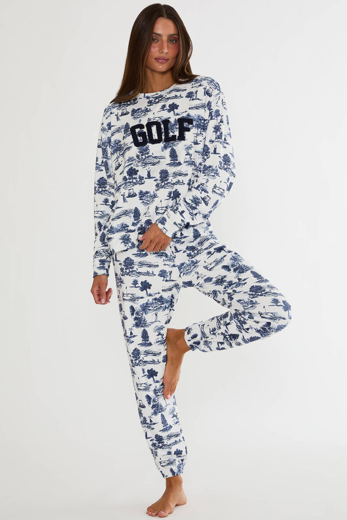Woman wearing a long-sleeve top and pants with a blue pattern and 'GOLF' text on a white background