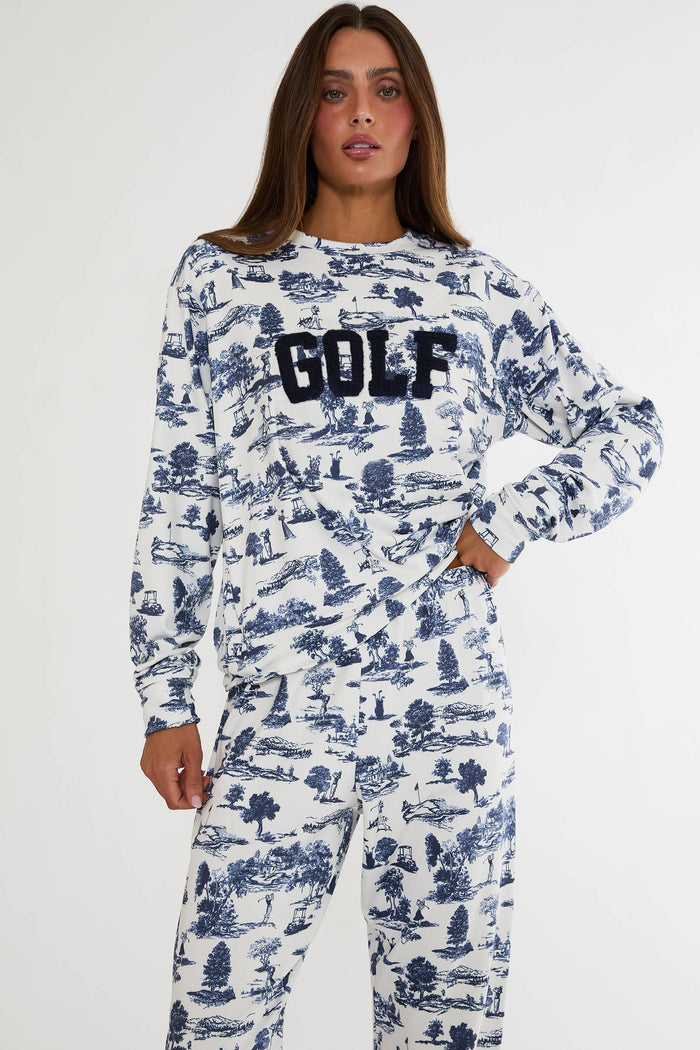 Person wearing a white long-sleeve shirt with blue pattern and 'GOLF' text, paired with matching pants on a white background.