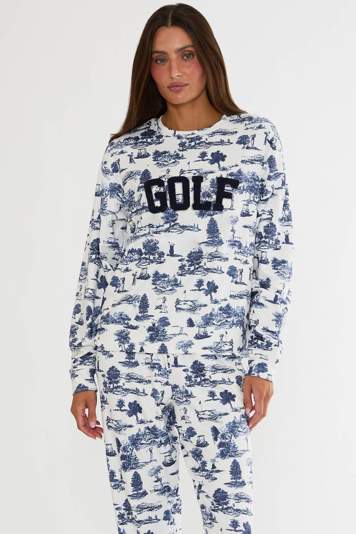 Woman wearing a white long-sleeve shirt with blue pattern and 'GOLF' text on a white background