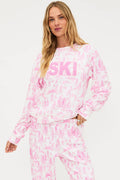 Woman wearing a pink and white tie-dye 'SKI' sweatshirt on a white background