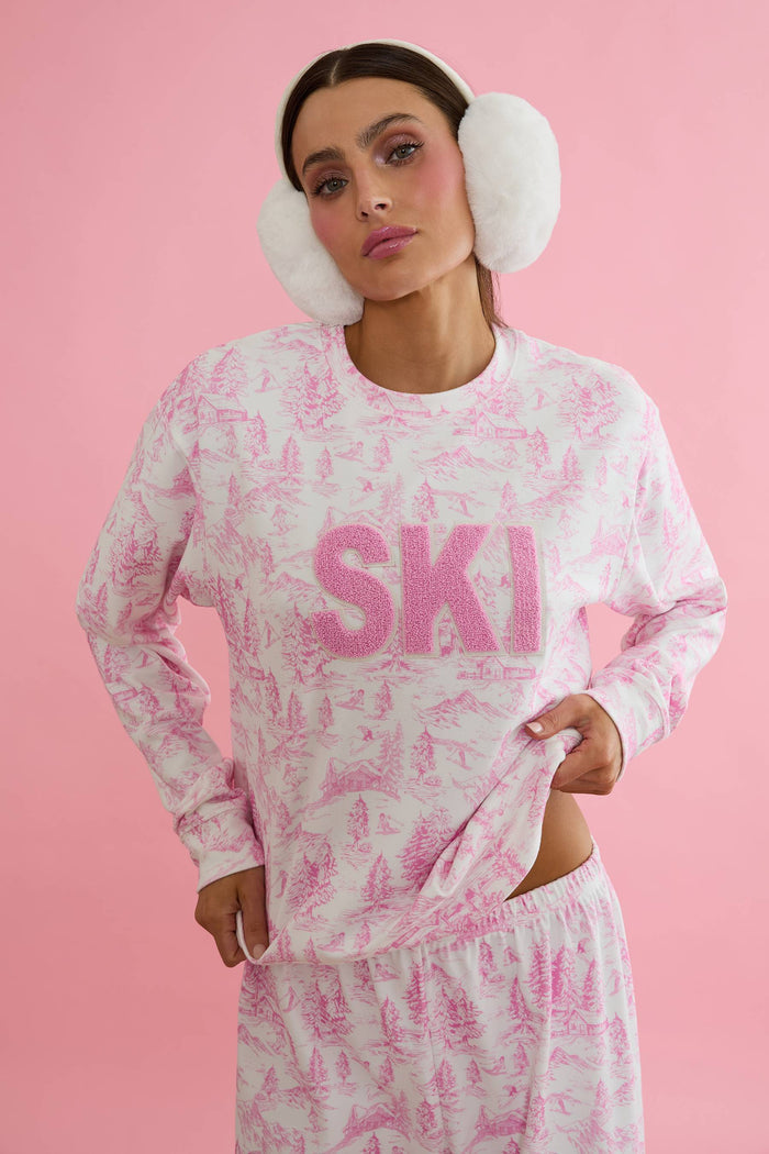 Woman wearing a pink and white tie-dye 'SKI' sweatshirt on a white background