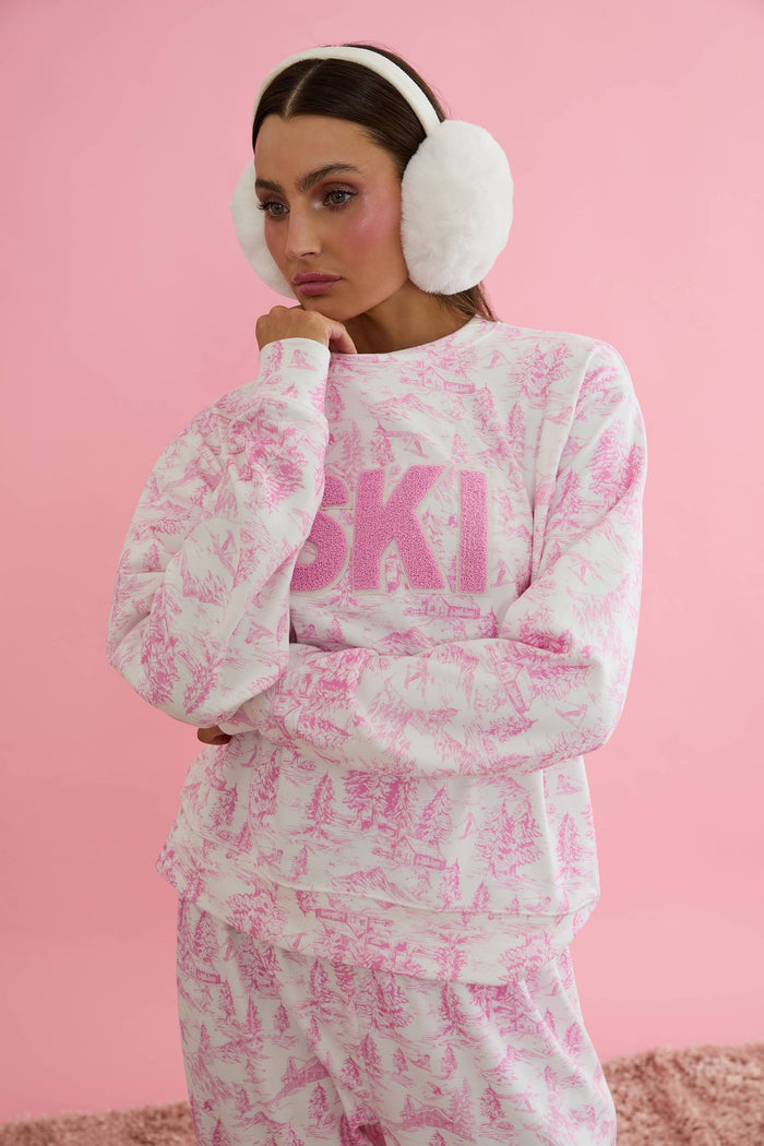 Woman wearing a pink and white tie-dye 'SKI' sweatshirt on a white background