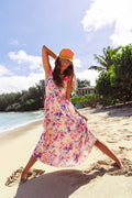 Woman in a floral dress and yellow hat on a beach