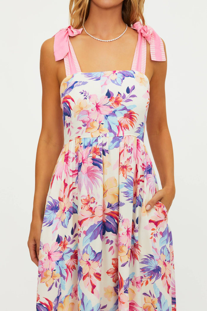 Woman wearing a colorful floral dress with pink ribbon straps on a white background