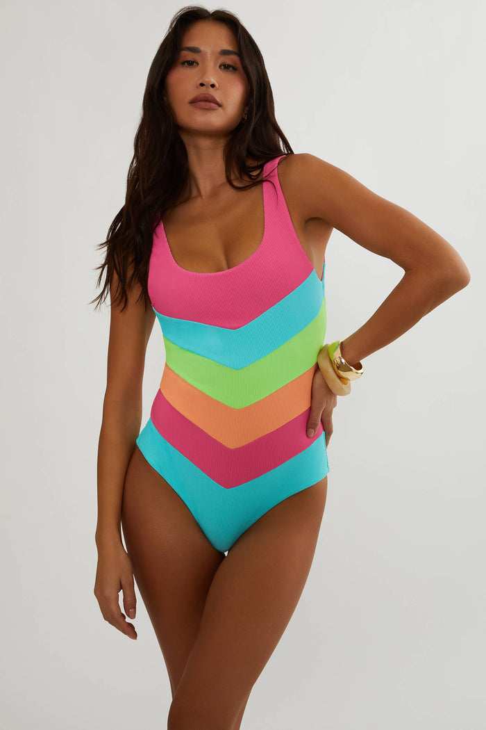 Woman wearing a colorful chevron-patterned swimsuit on a plain background