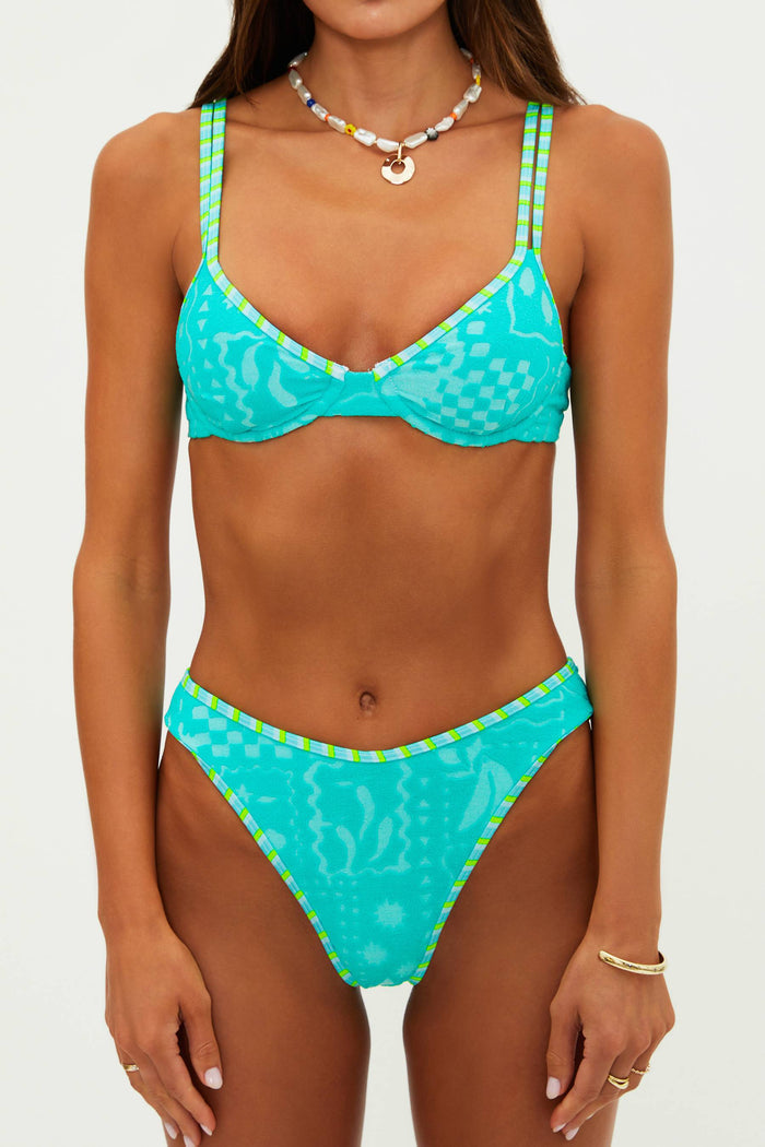 Woman wearing a turquoise bikini with green accents on a white background