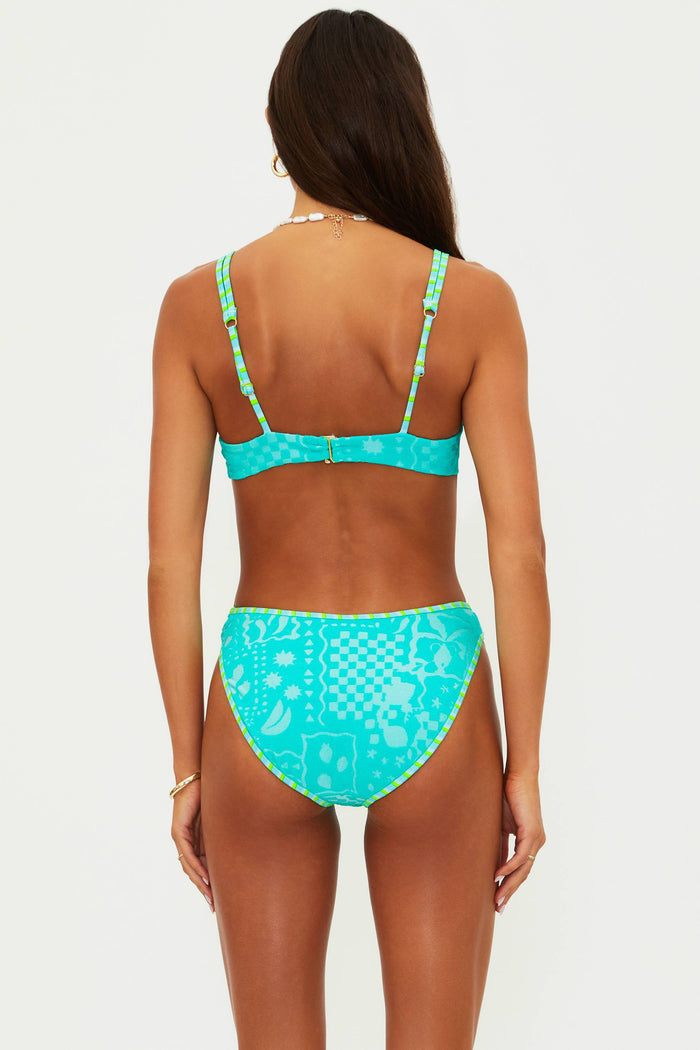 Woman wearing a turquoise bikini with a white pattern on a light gray background