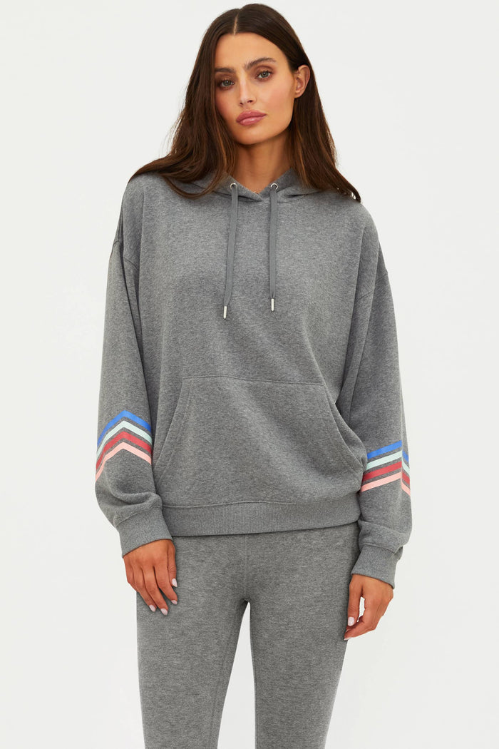 Woman wearing a gray hoodie with colorful sleeve stripes on a white background