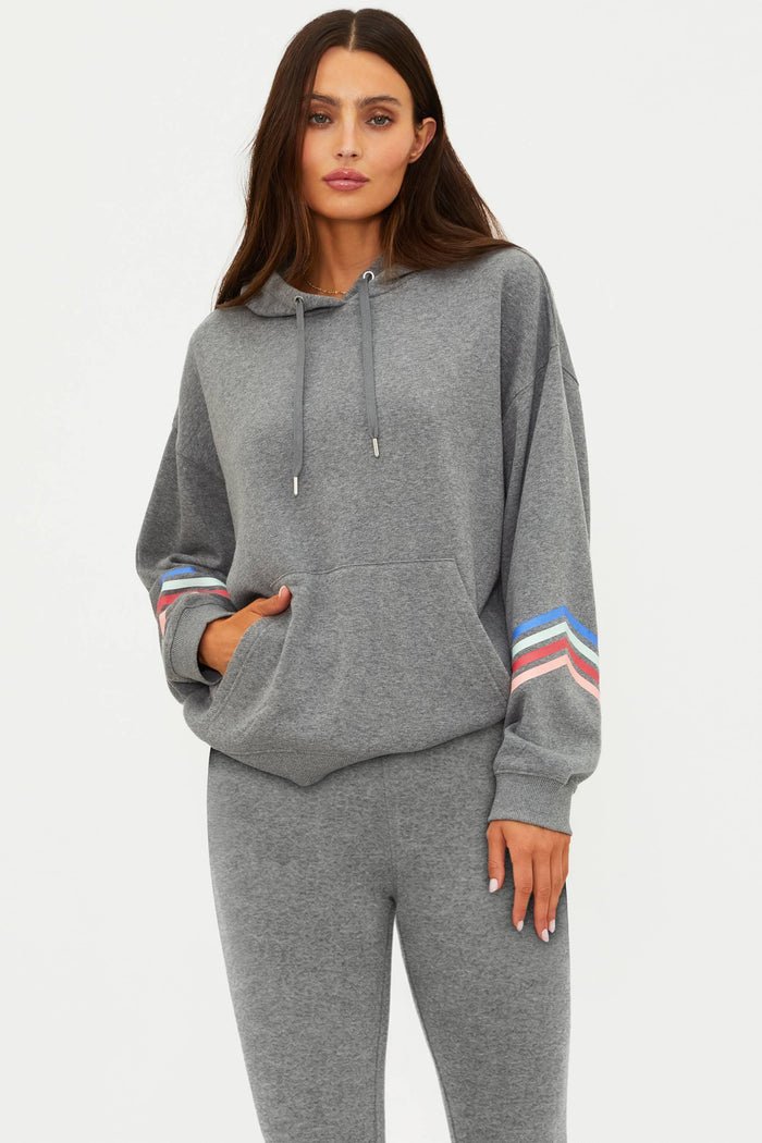 Woman wearing a gray hoodie with colorful stripes on sleeves against a white background