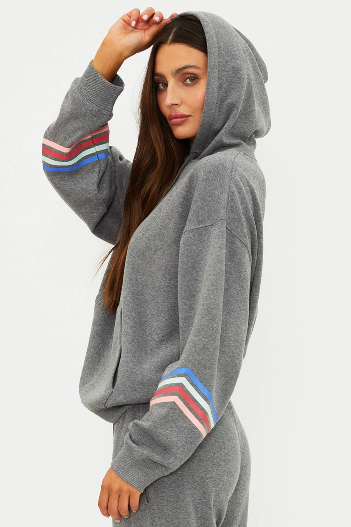 Person wearing a gray hoodie with colorful stripes on sleeves against a white background