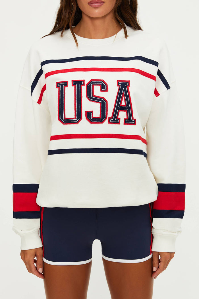 White sweatshirt with 'USA' text and red and blue stripes worn by a person on a white background