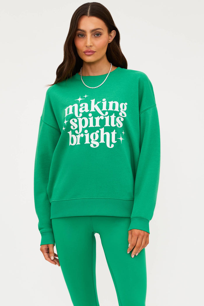 Woman wearing a green sweatshirt with 'making spirits bright' text on a white background