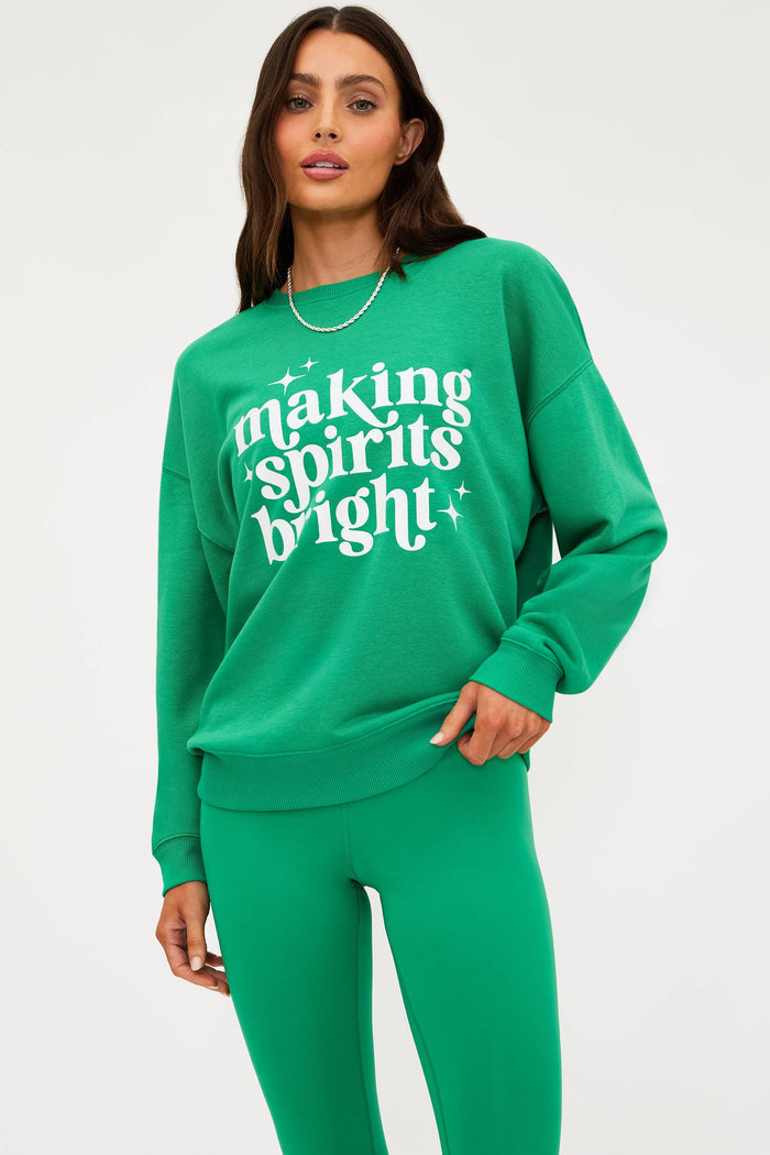 Woman wearing a green sweatshirt with 'making spirits bright' text on a white background