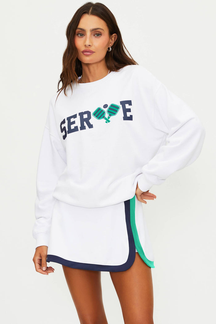 Woman wearing a white sweatshirt with 'SERVE' printed on it against a plain background