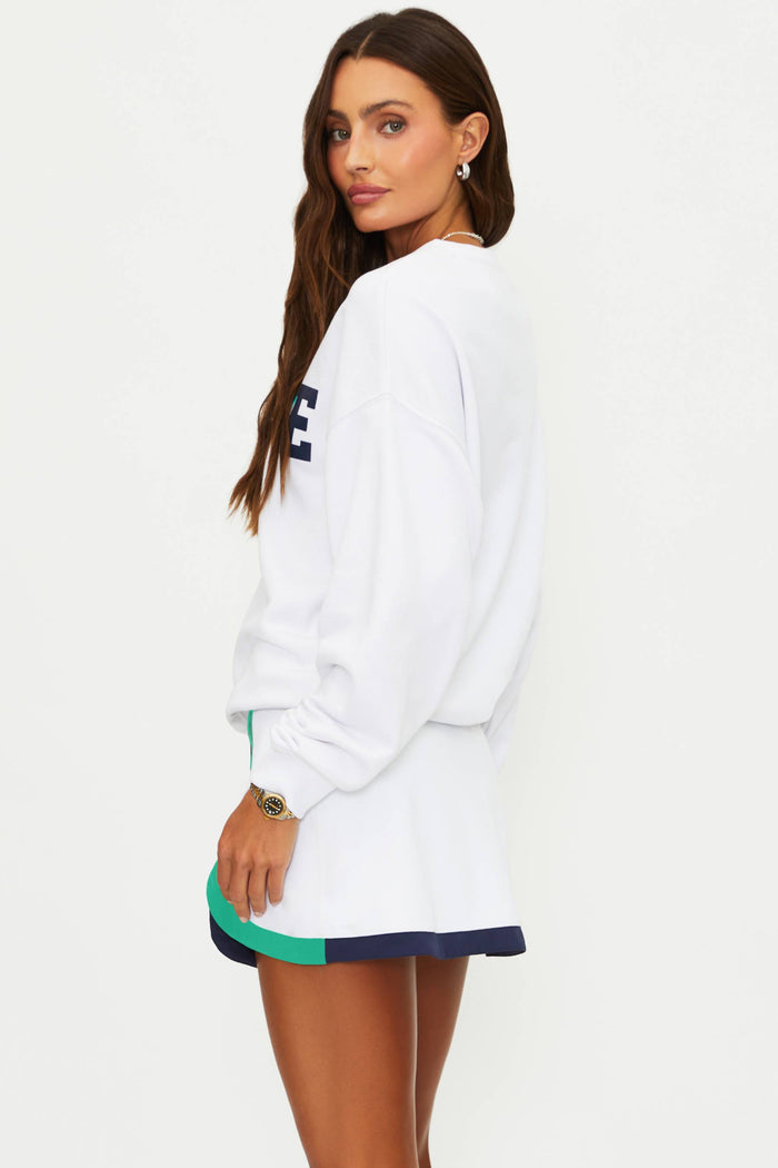 Woman wearing a white sweatshirt with a logo on a plain background