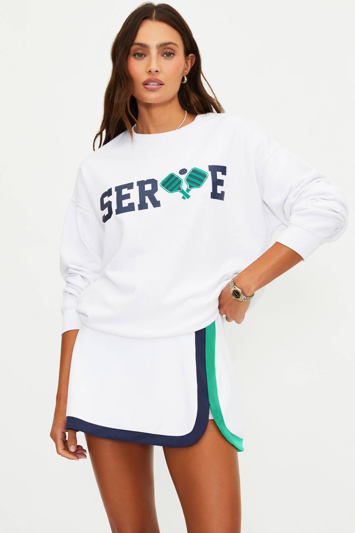 Woman wearing a white sweatshirt with 'SERVE' and tennis racket graphics on a white background