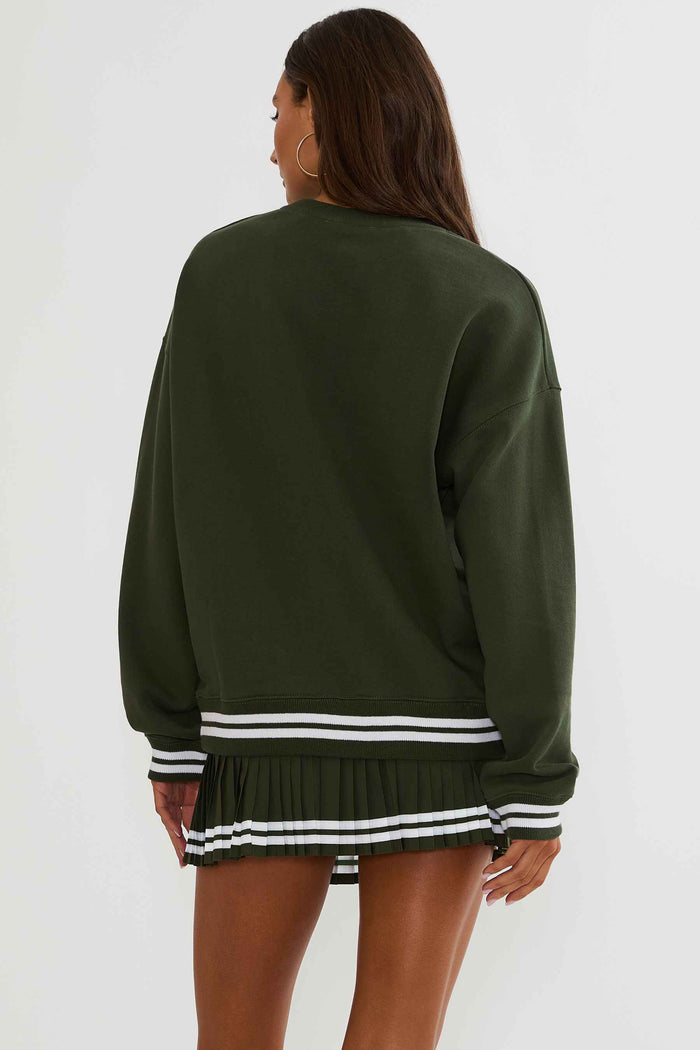 Woman wearing a green sweatshirt with white text "apres tennis"