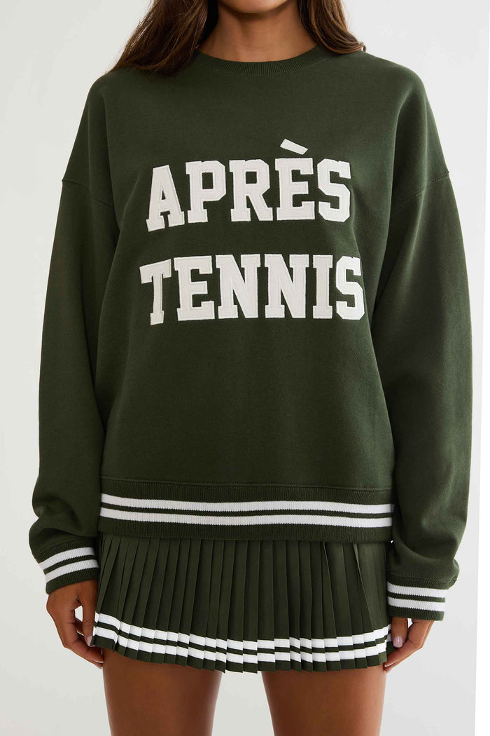 Woman wearing a green sweatshirt with white text "apres tennis"