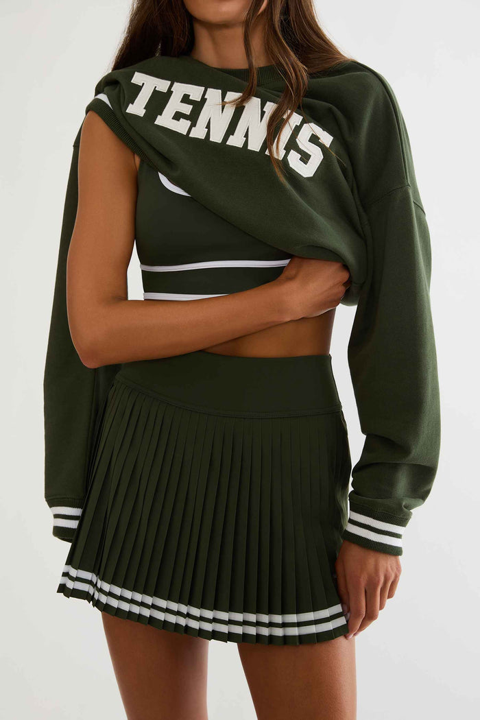 Woman wearing a green sweatshirt with white text "apres tennis"