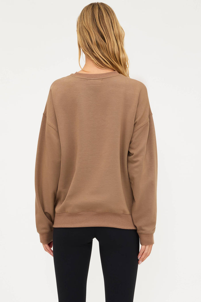 Woman wearing a beige sweatshirt with 'SPOOKY' text on a white background