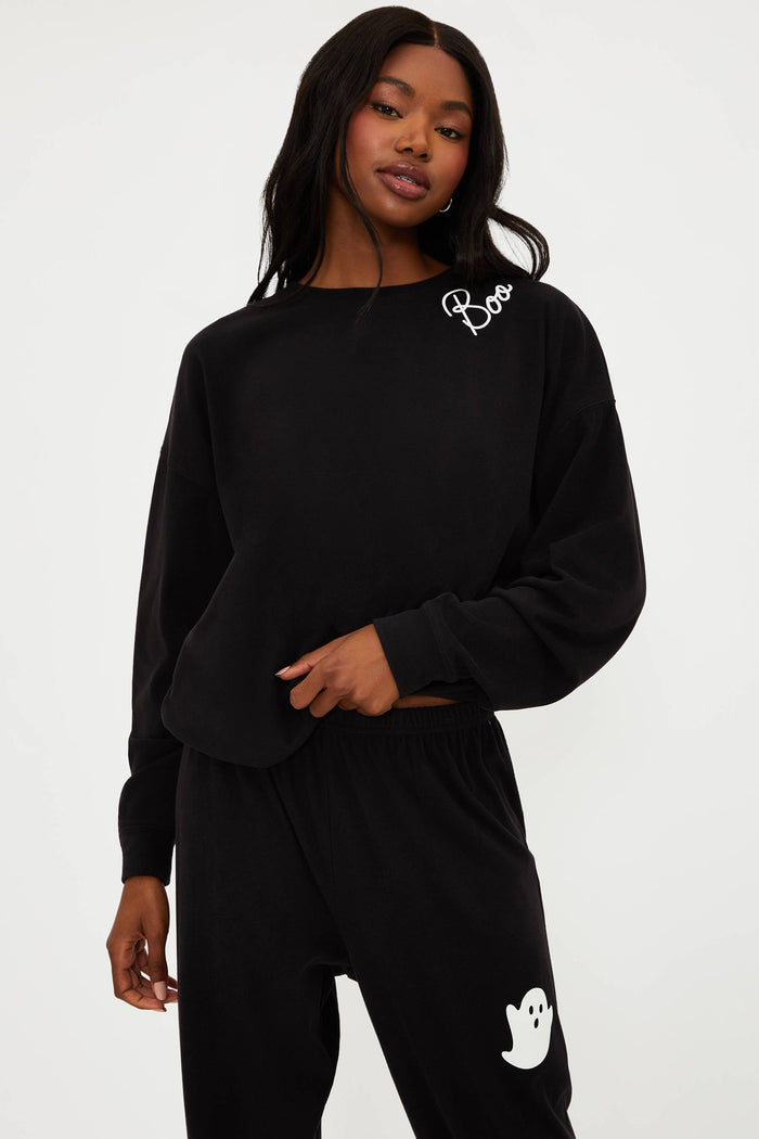 Person wearing a black outfit with white branding on a plain background