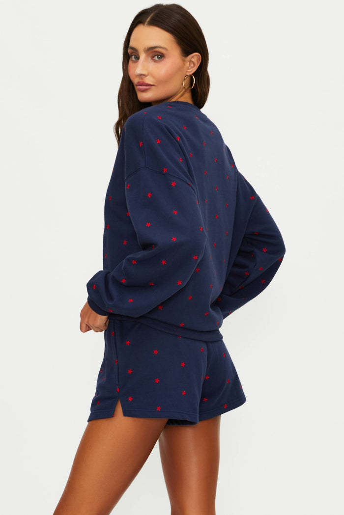 Woman wearing a navy blue outfit with red heart patterns on a white background