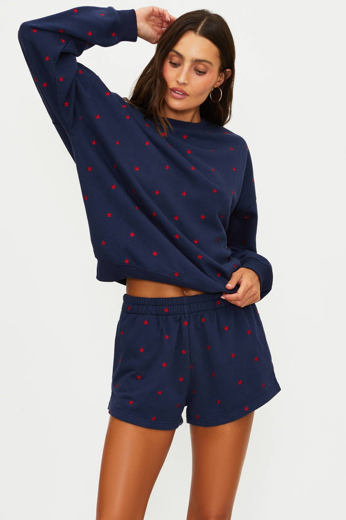 Woman wearing a navy blue outfit with red heart patterns on a white background