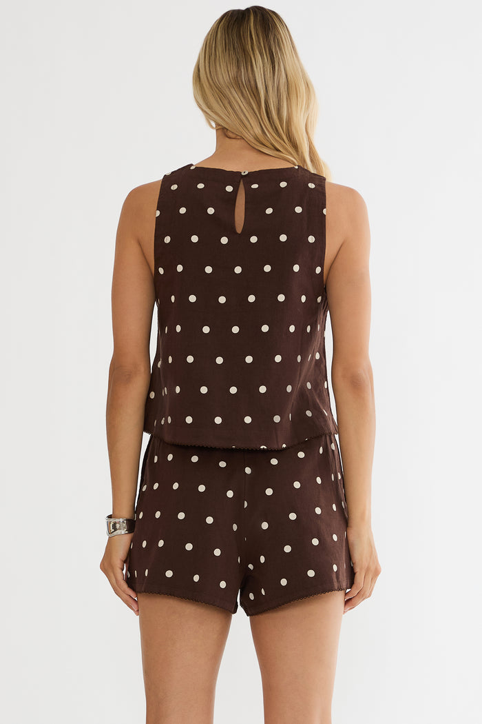 Woman wearing a brown polka dot top and shorts set on a white background
