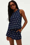 Model wearing a navy sleeveless top with white polka dots, paired with matching shorts, accessories include sunglasses and a watch.