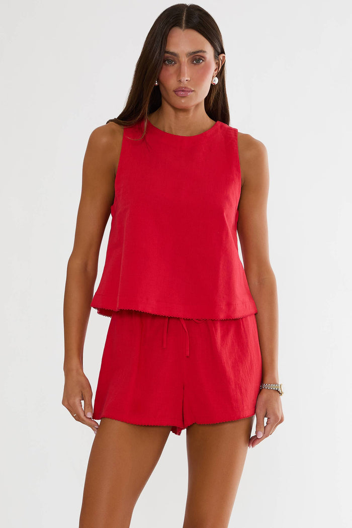 Woman wearing a red sleeveless top and shorts on a white background