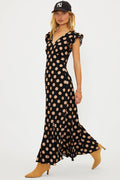 Woman wearing a black polka dot dress with beige dots on a white background